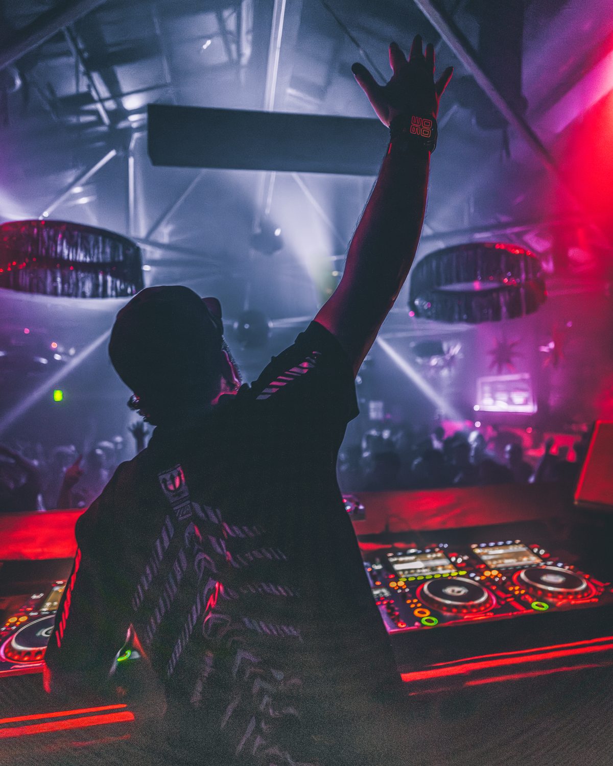 Mac Vaughn behind the decks, arm raised to the crowd